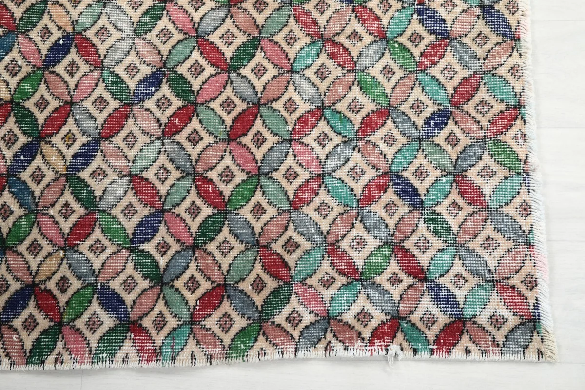 Detailed view of the multicolor interlocking geometric design and fringed edge of the rug