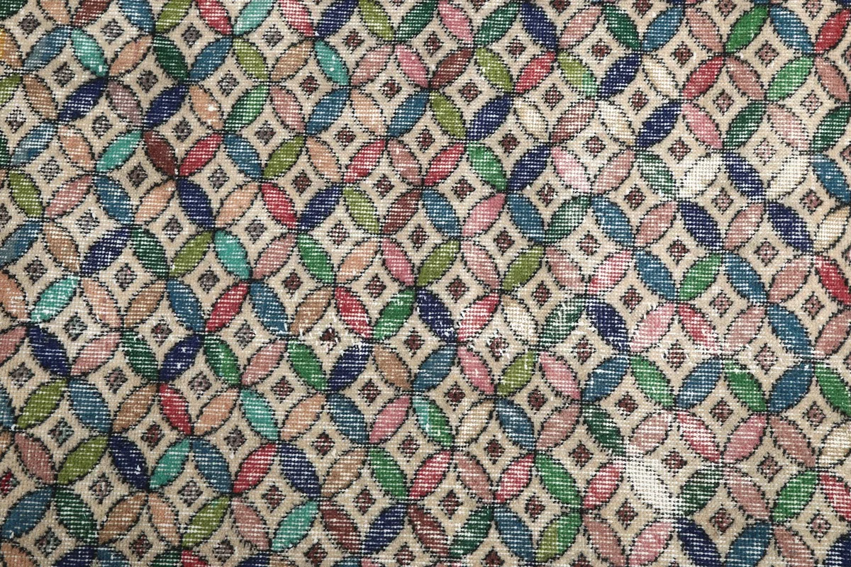 Close-up of the intricate multicolor geometric pattern with faded colors and visible wear