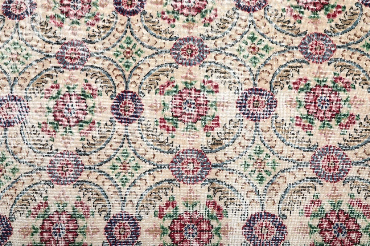 Close-up detail of the hand-knotted floral medallions in rose, purple, green, and blue