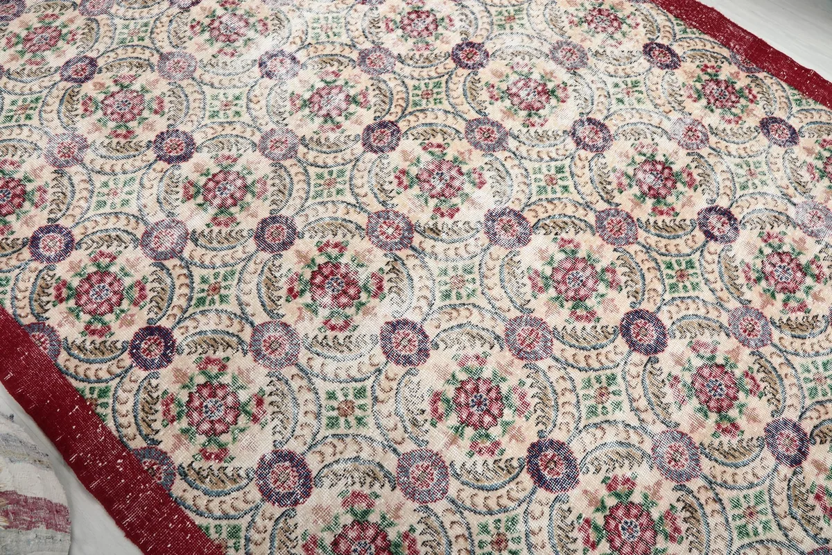 Overhead view of the rug's repeating floral medallion pattern and cream field