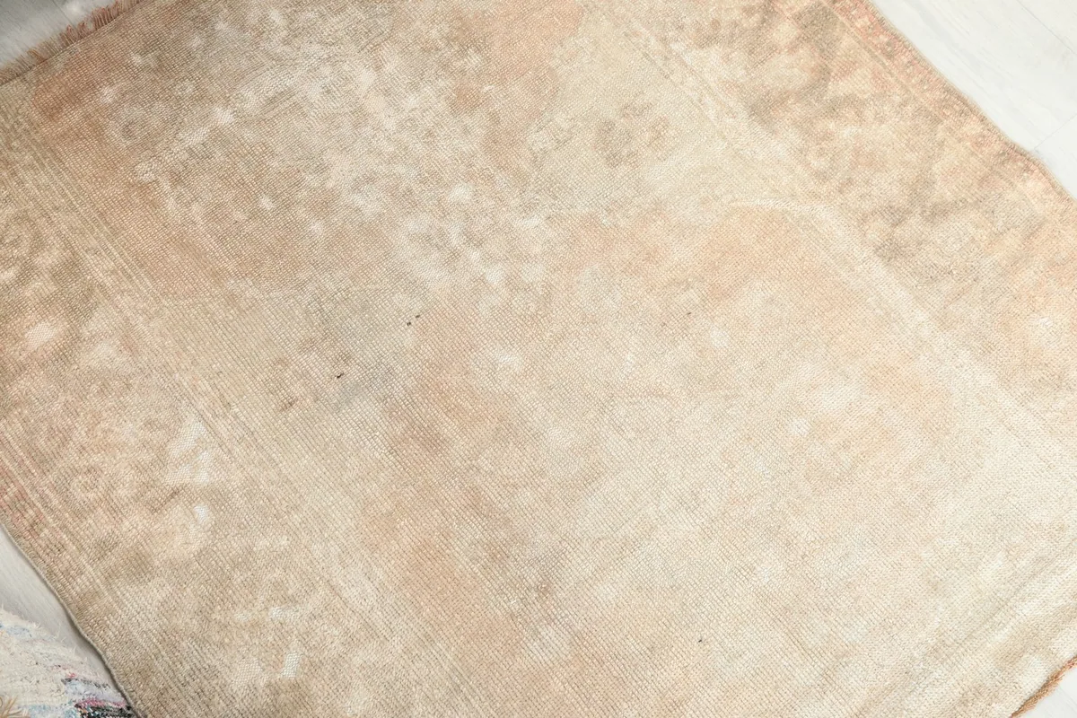 Detailed view of the rug's surface, highlighting the distressed texture and muted beige and tan colors