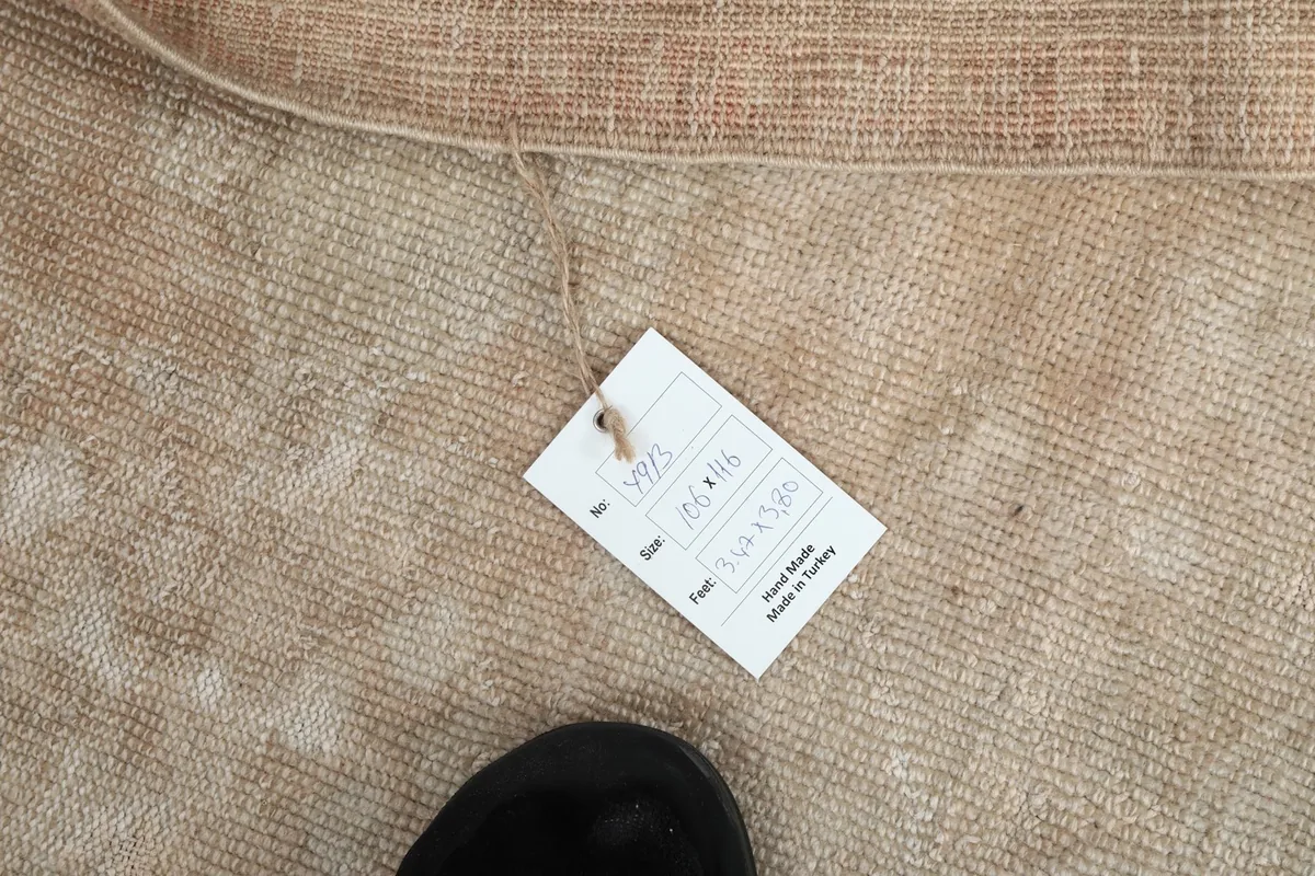 Rug with its product tag, displaying size and origin details next to the hand-knotted weave