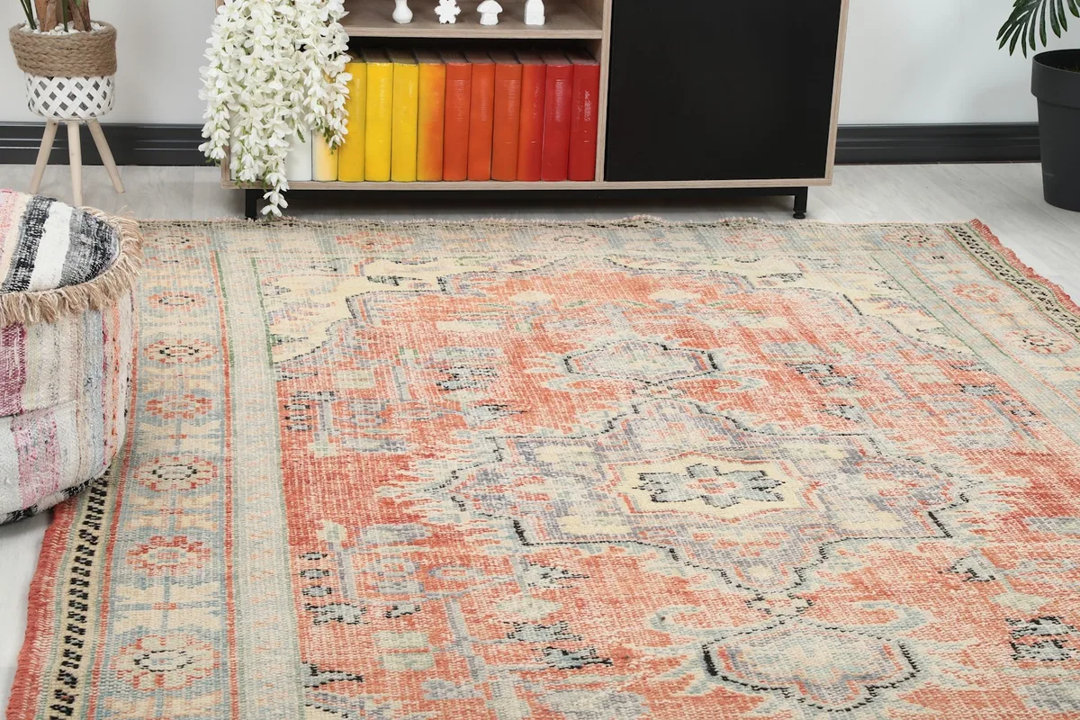 Close-up view of the rug's rust field and medallion pattern from an angle in a room setting.
