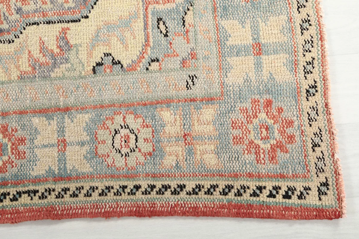 Detail of the rug's ivory and blue border with floral and geometric elements.