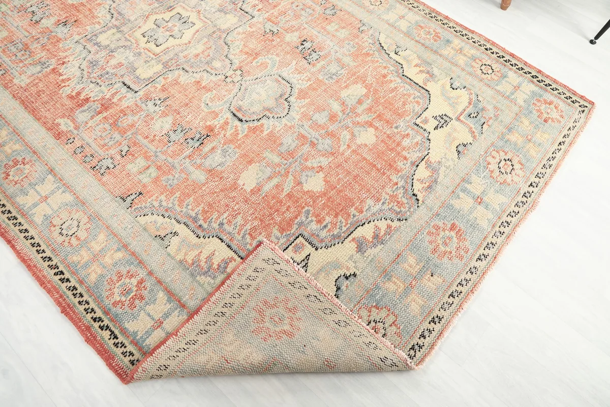 Corner of the rug folded back, revealing the hand-knotted wool pile and cotton foundation.