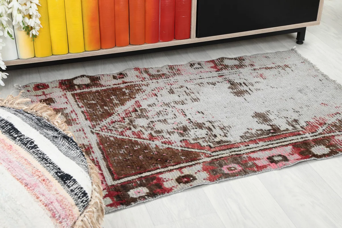 Close-up angle of the rug's design and colors in a room setting, next to a colorful bookshelf.
