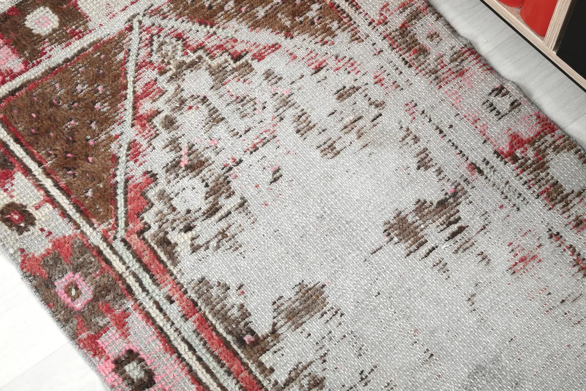 Detail view of the faded gray field and brown geometric design of the vintage rug.