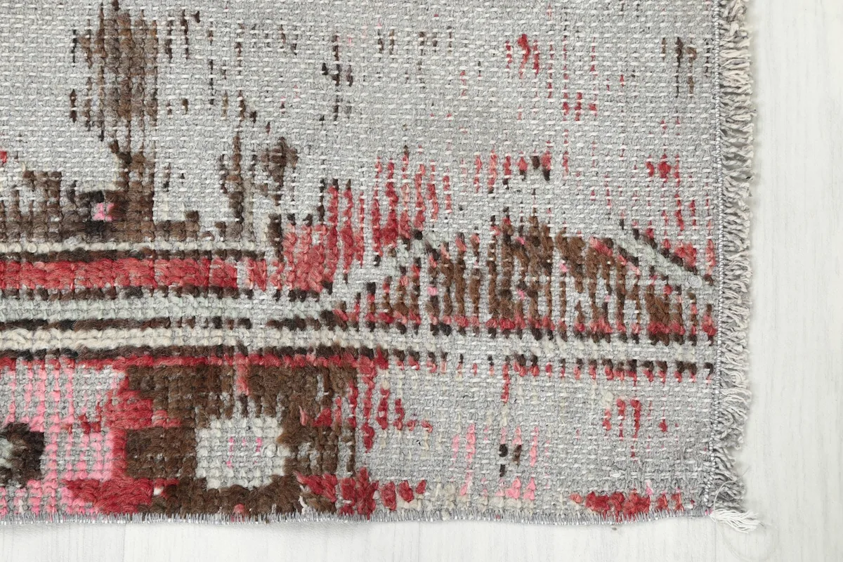 Corner detail of the rug, showing the short, natural fringe and border design.