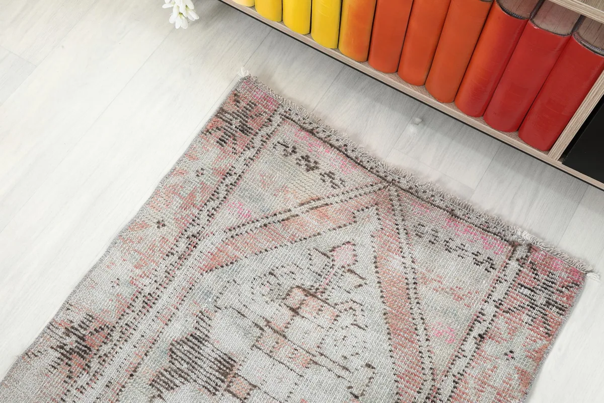 Overhead angled shot of the rug's end, showing its placement next to a colorful shelf