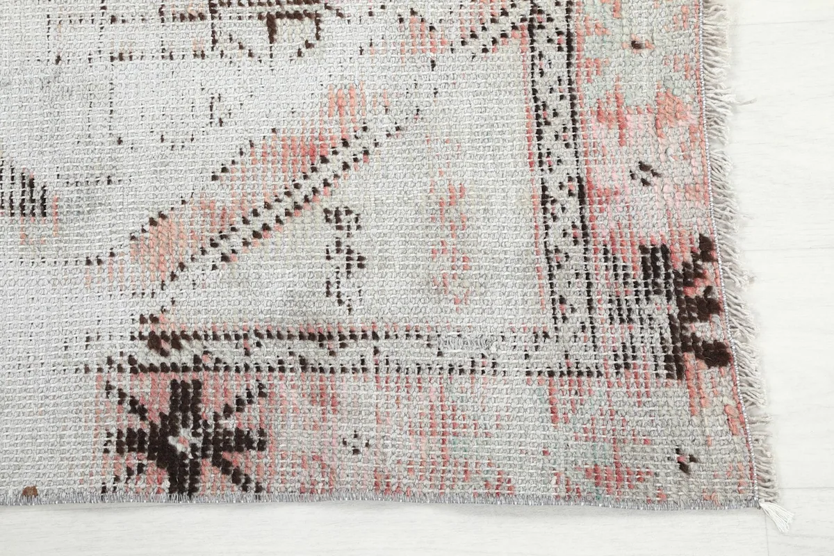 Detailed view of the corner of the rug, showing faded rose and geometric patterns