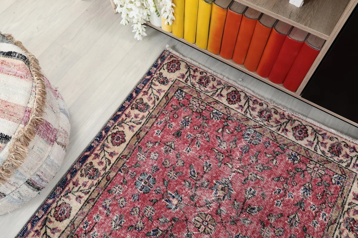 Overhead view of the rug in a room, showing its texture and colors next to a bookshelf