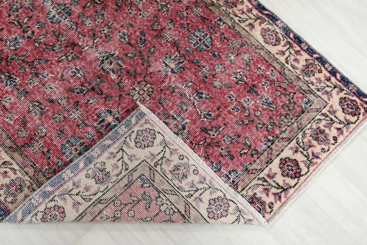 A corner of the rug folded back, revealing the reverse side and the hand-knotted construction