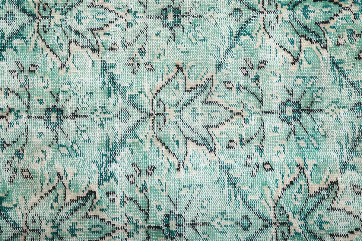Close-up of the hand-knotted wool pile and faded green and blue colors