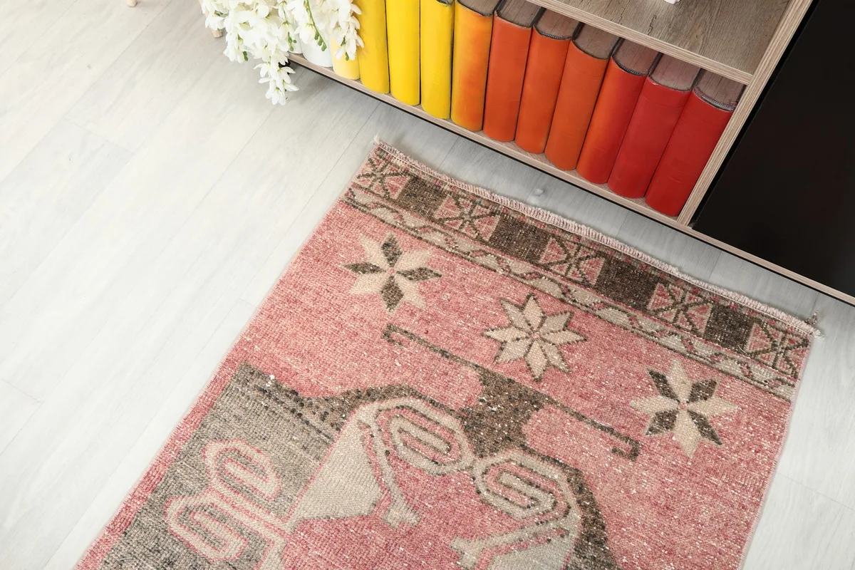 Angled view of the runner's end, showing the brown and beige border and a section of the main rose and gray pattern.
