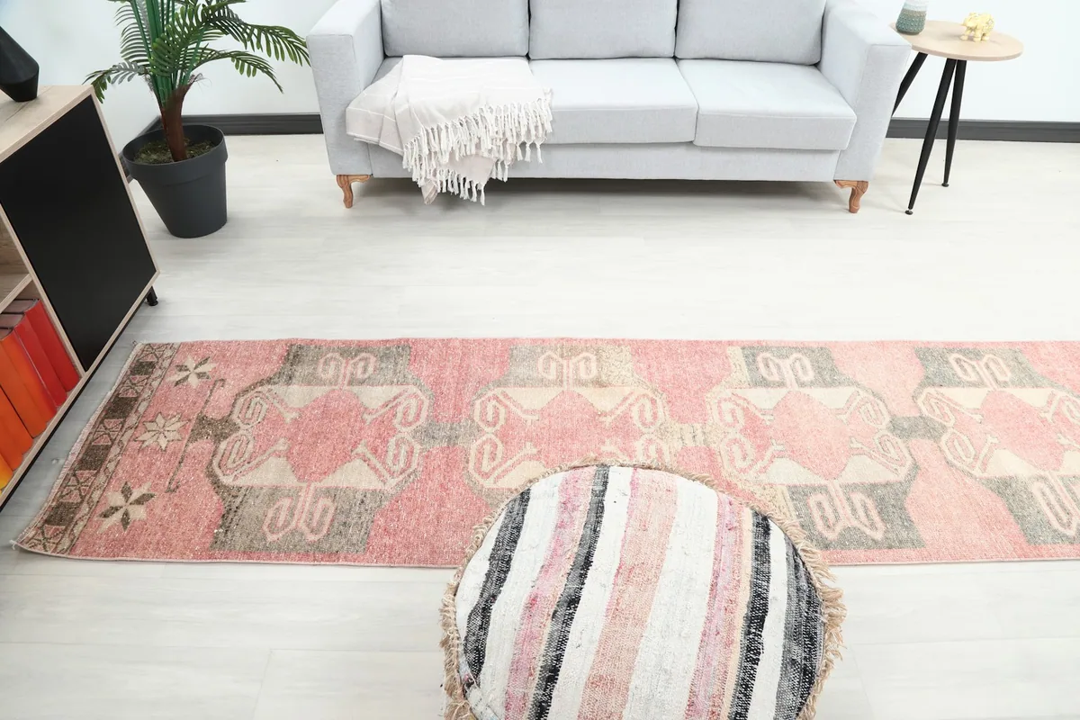 Full view of the runner in a living area, demonstrating its scale and pattern alongside a gray sofa and pouf.