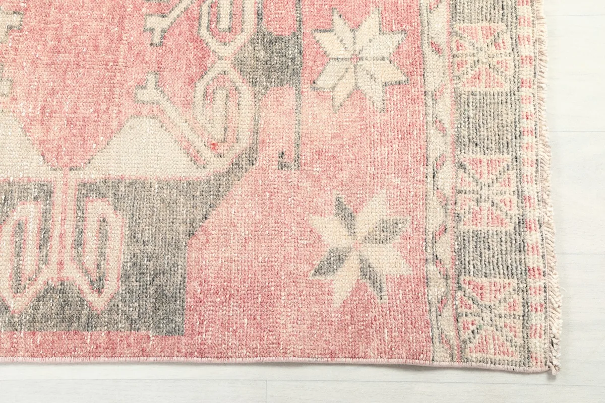 Close-up detail of the runner's end, showing faded rose, gray, and beige geometric stars and border pattern.