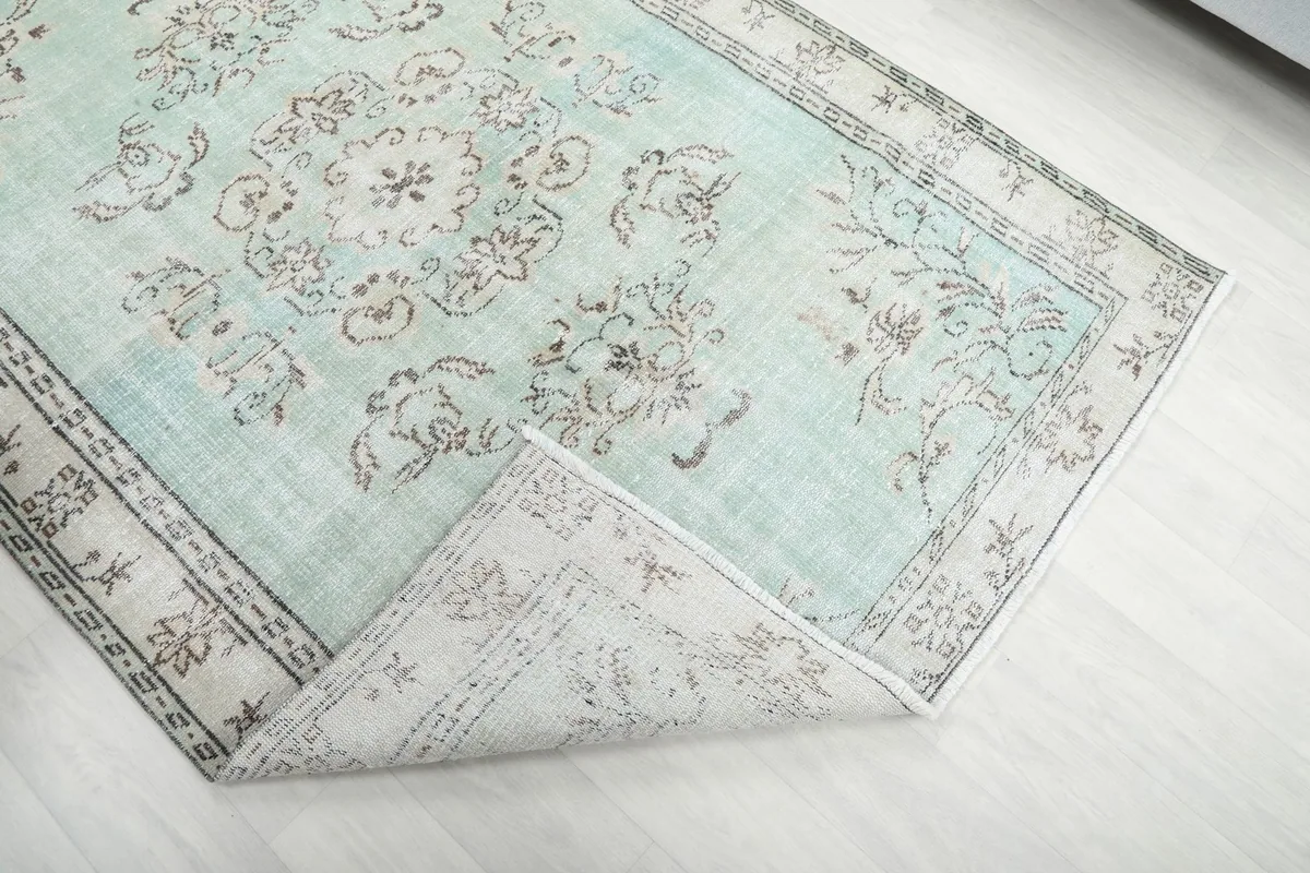 Corner of the rug folded back, revealing the reverse side of the hand-knotted foundation