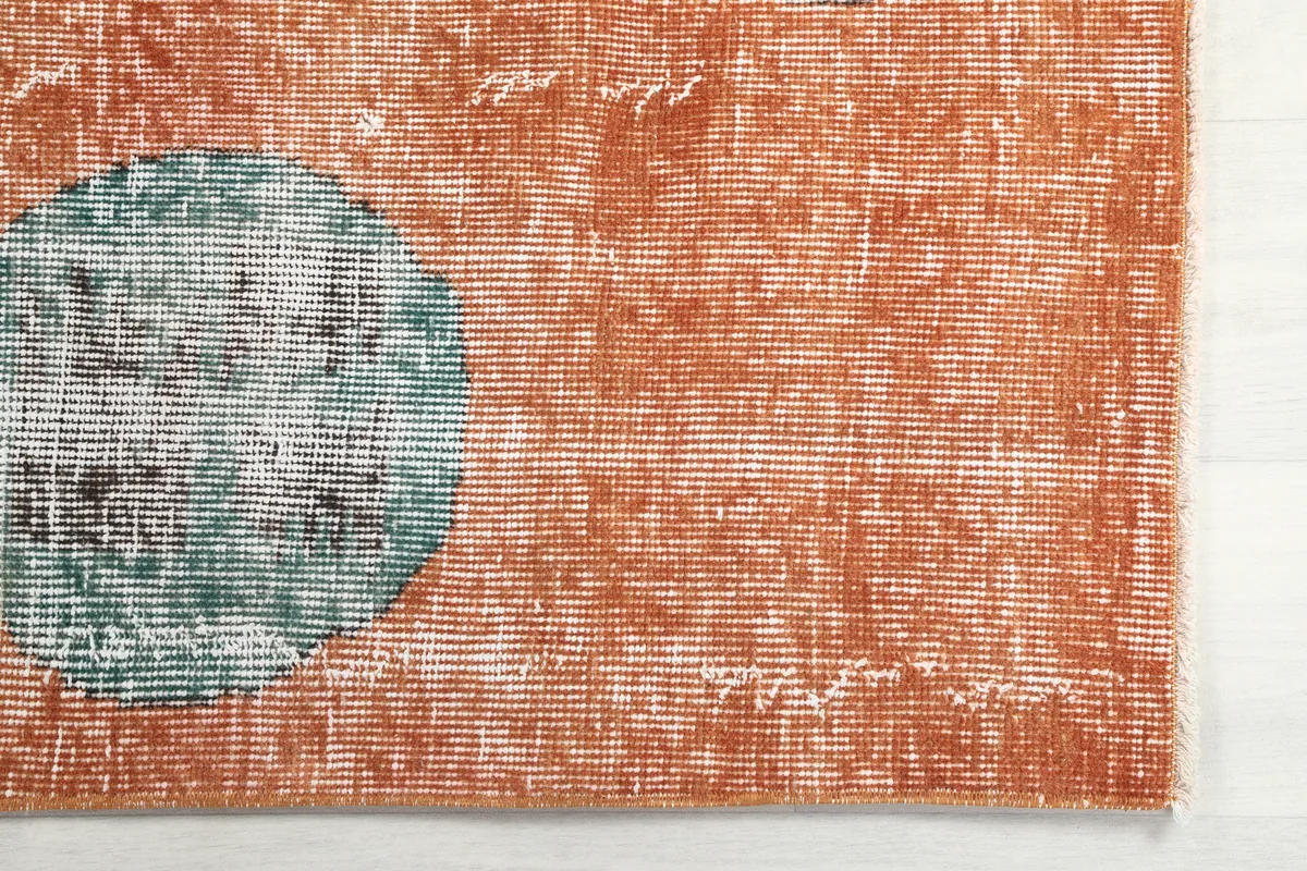 Close-up of the Rust Geometric Oval Runner showing the distressed texture and a green oval motif.