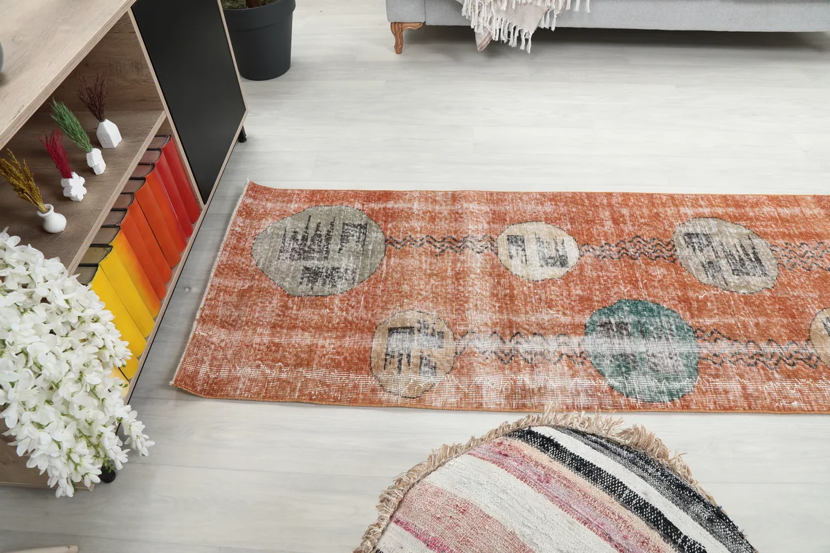Rust Geometric Oval Runner in a room, viewed from an angle, emphasizing its length and visual impact.