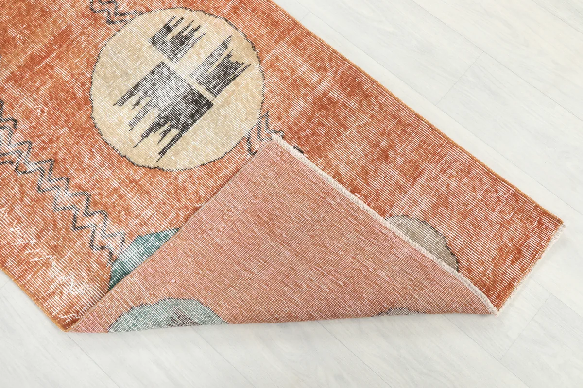 Rust Geometric Oval Runner flipped to show the hand-knotted cotton foundation and the back of the wool pile.