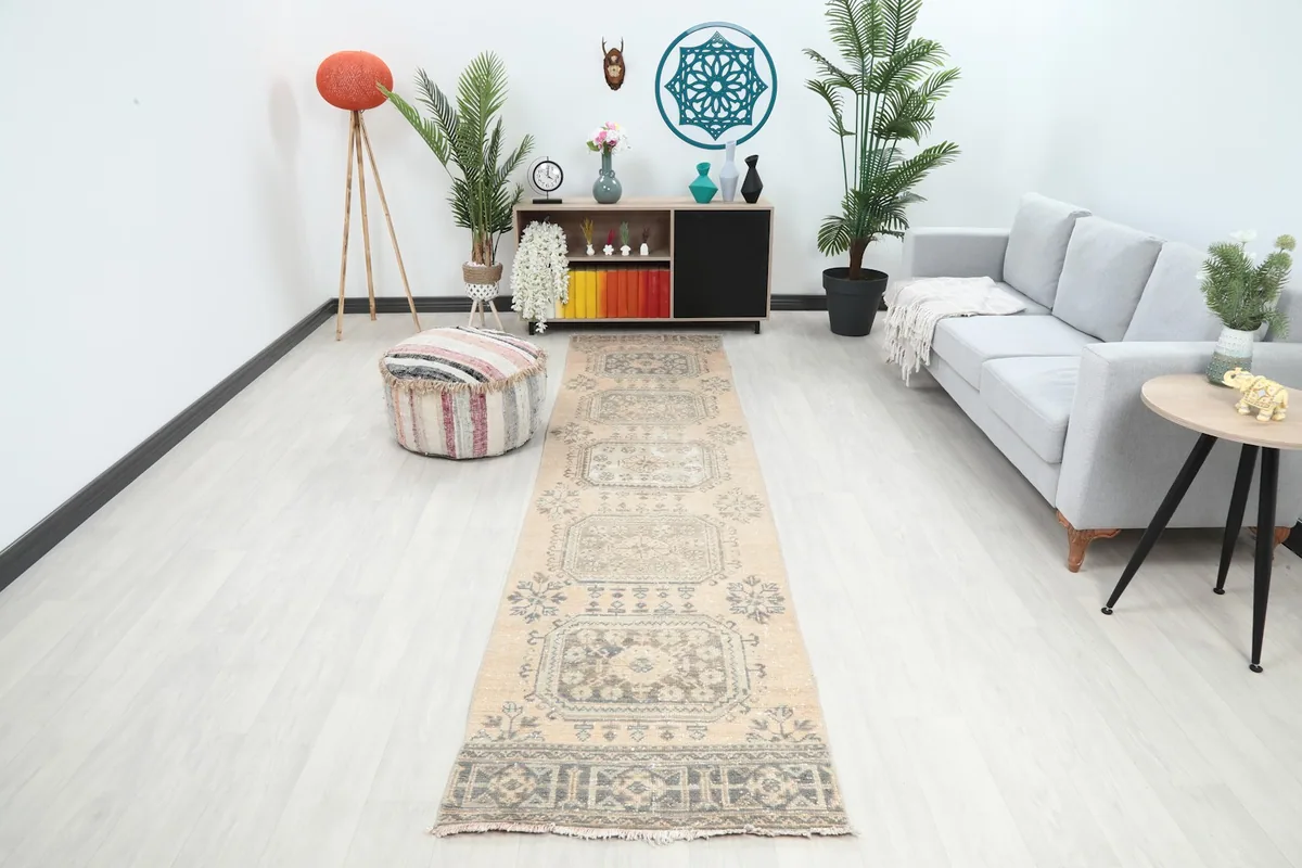 Runner rug featuring tan and charcoal geometric motifs in a modern hallway with a gray sofa.