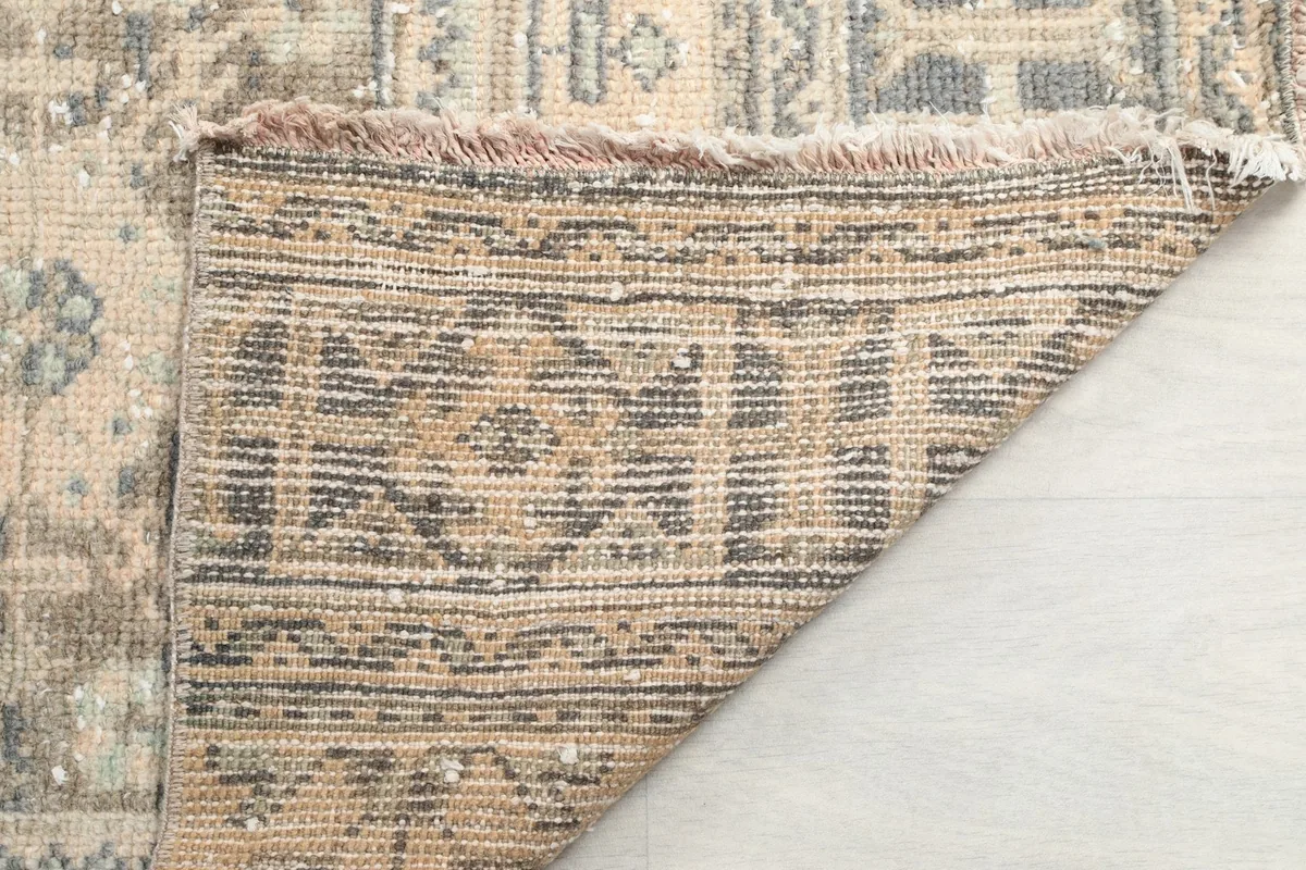 Underside view of the rug, showing the tight hand-knotted cotton foundation and fringe.