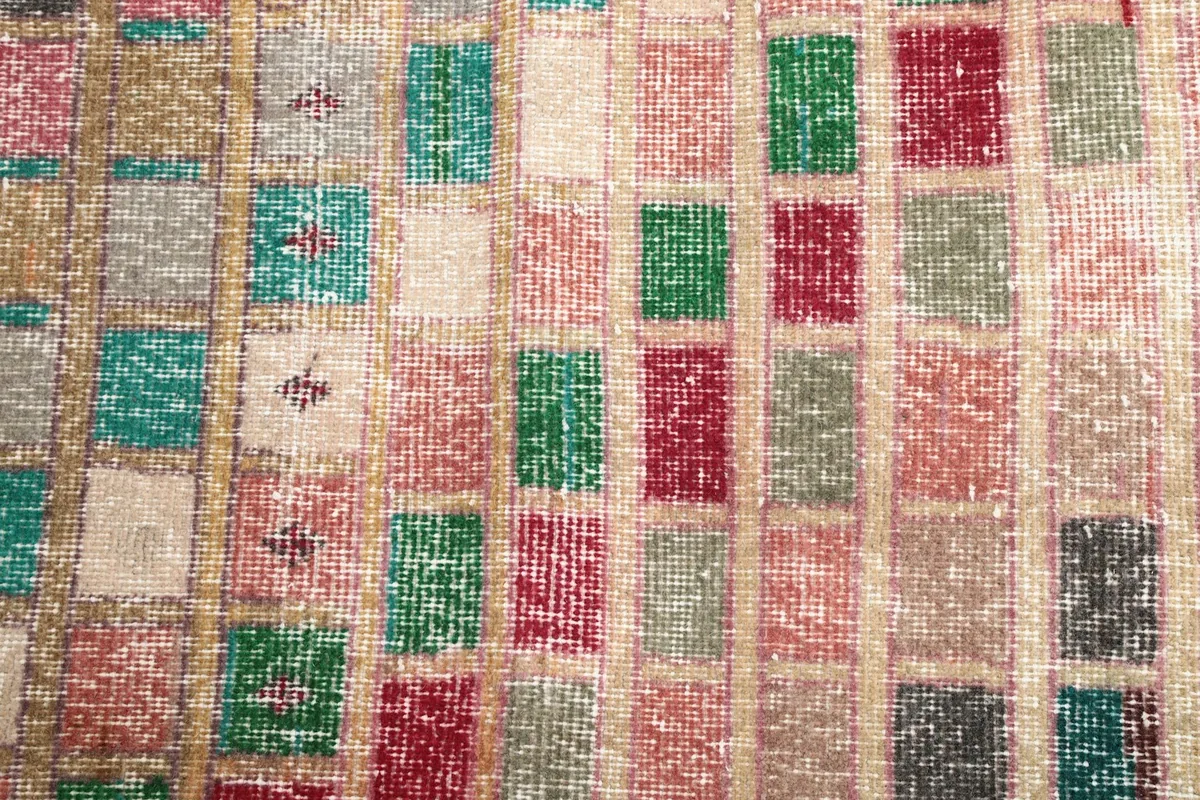 Close-up of the textured, low pile surface and individual colored squares of the rug