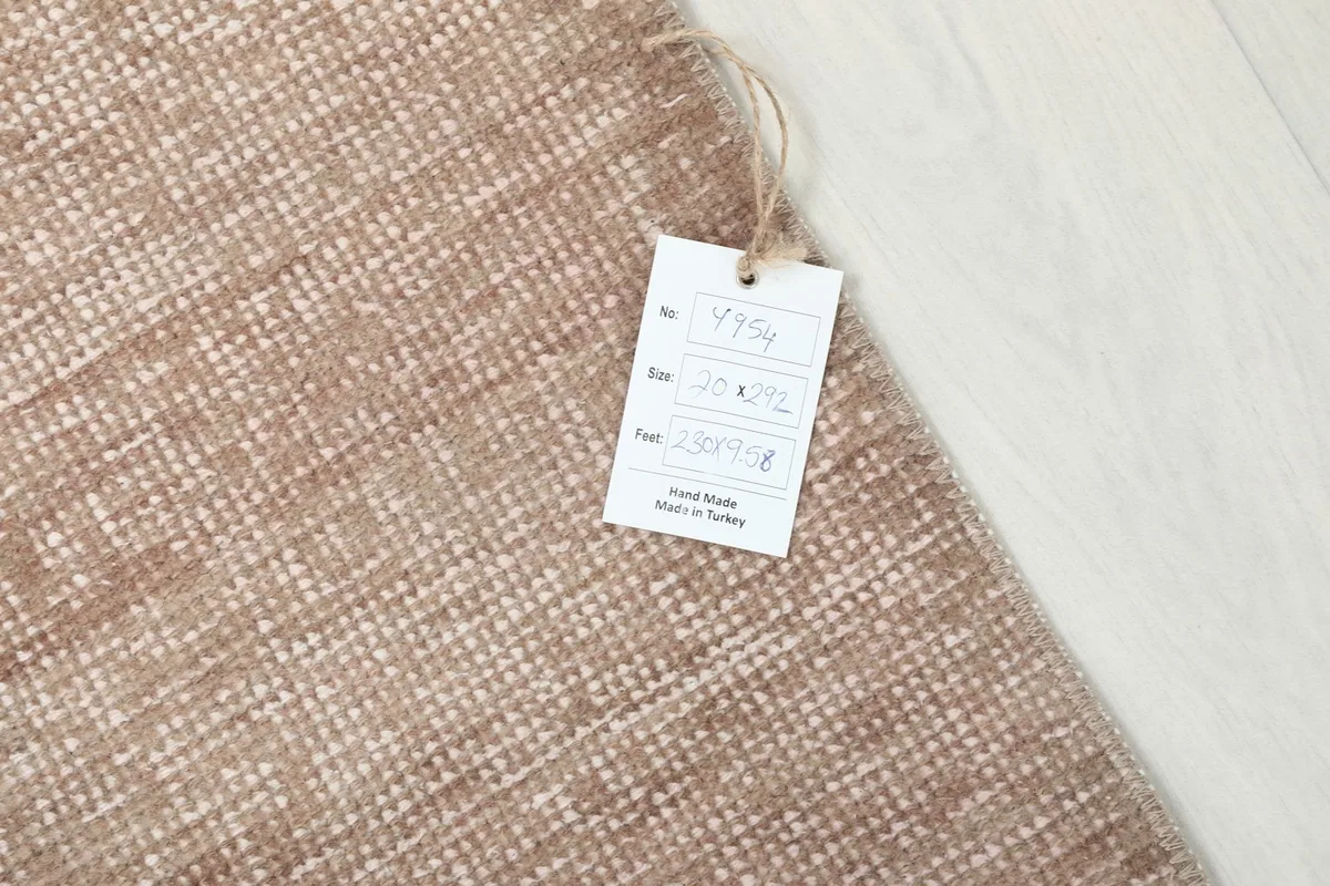 Detail of the rug's texture with a product tag, confirming its hand-knotted origin from Turkey