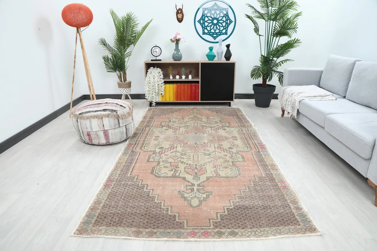 Vintage Anatolian rug with rose and brown tones in a modern living room setting with light flooring and furniture.