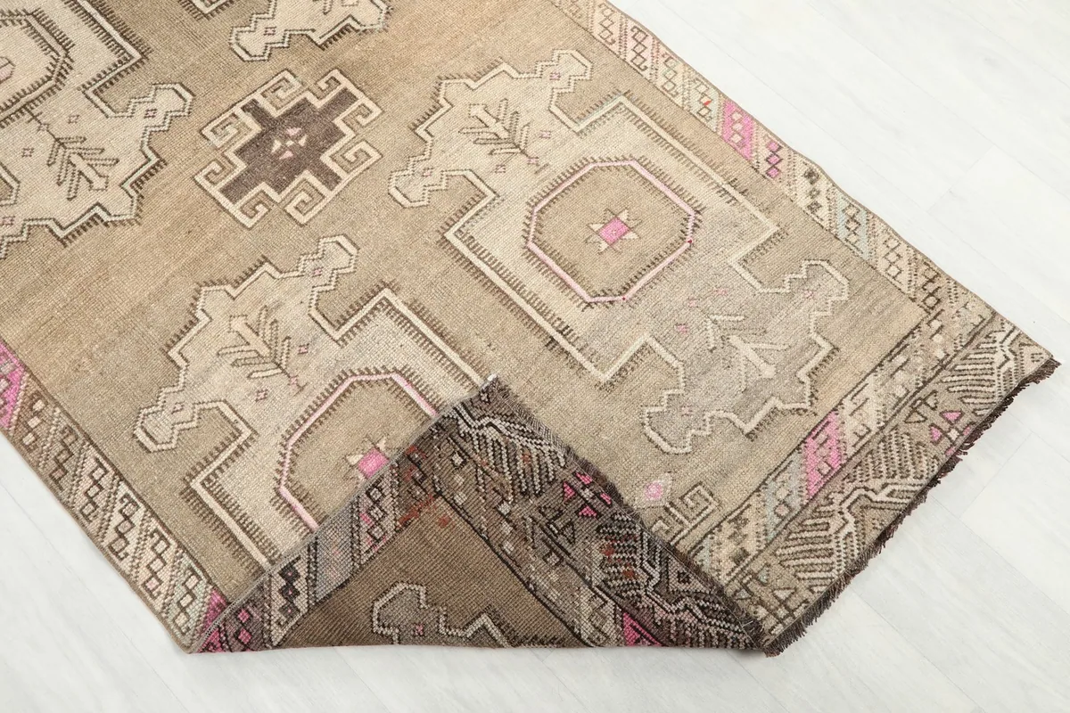 Corner of the rug folded to reveal the hand-knotted cotton foundation and the reverse side of the pattern.