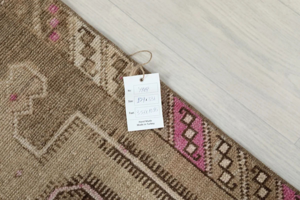 Close-up of the rug's edge with a product tag, showing the weave and a pink border detail.