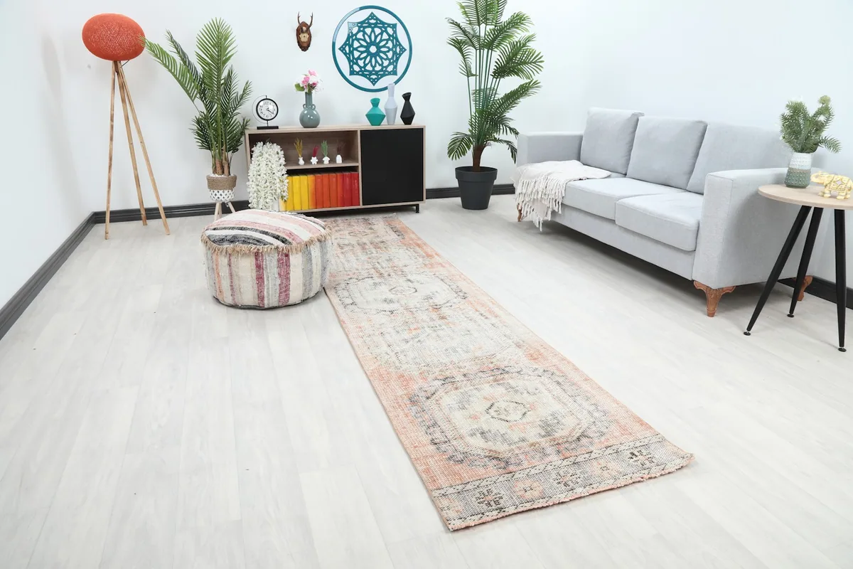 Angle view of the rust and gray runner rug in a living space with a sofa and ottoman