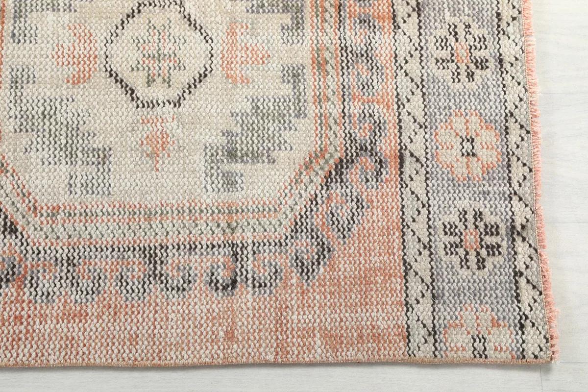 Detailed view of the rug's geometric border and central medallion in rust, gray, and ivory