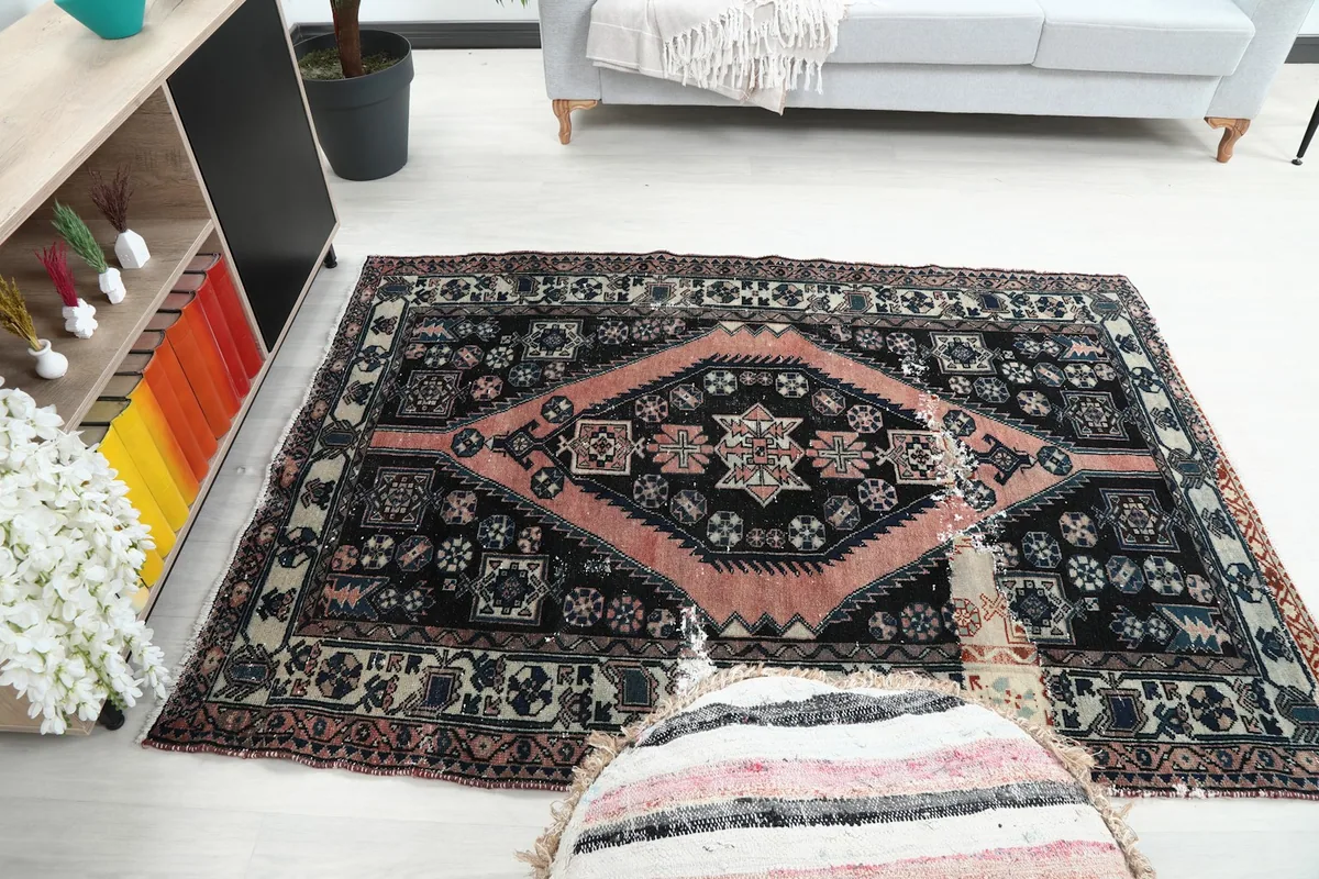 Wide angle view of the rose and black rug in a room, showing its full design and colors