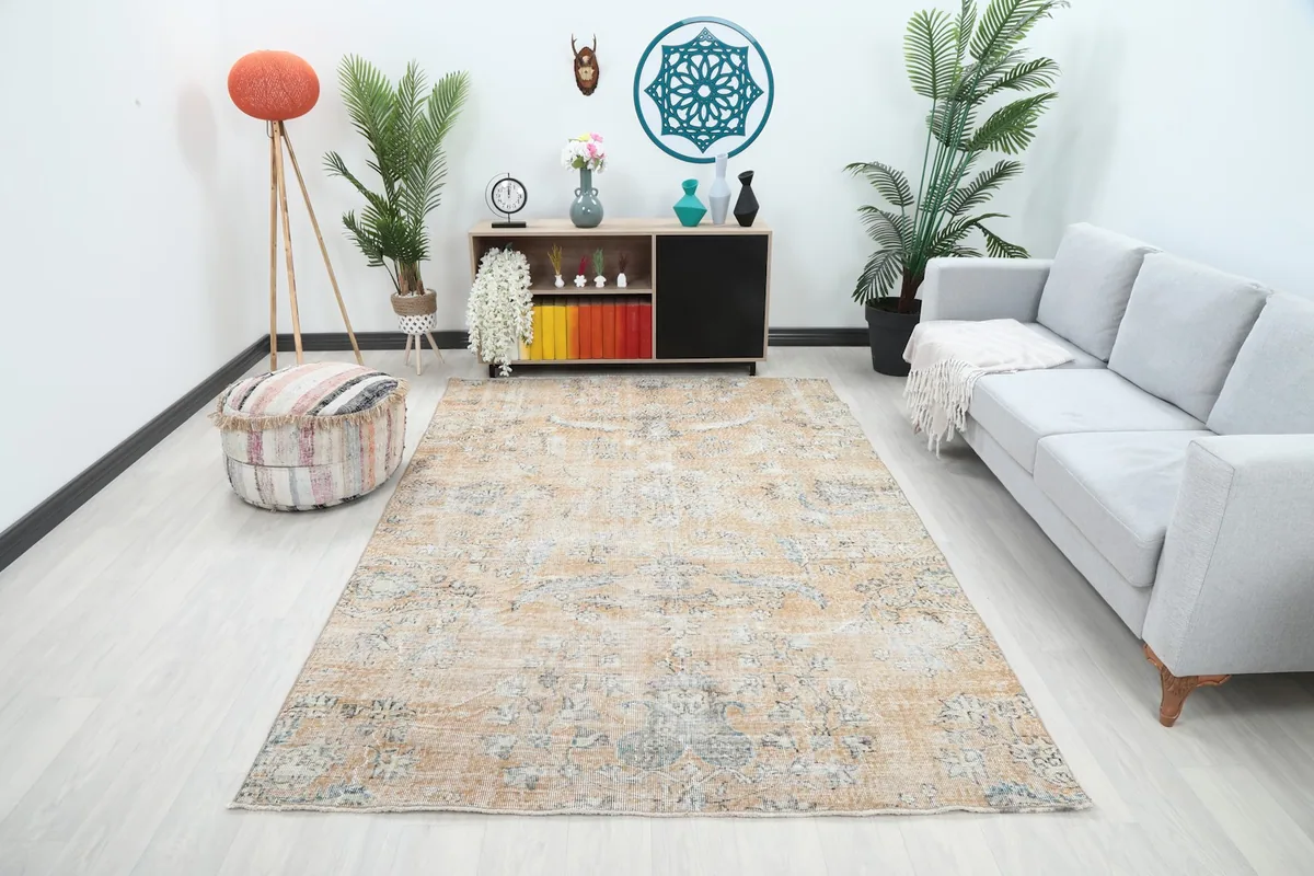 Vintage beige and blue rug placed in a modern living room setting with a gray sofa and wooden cabinet