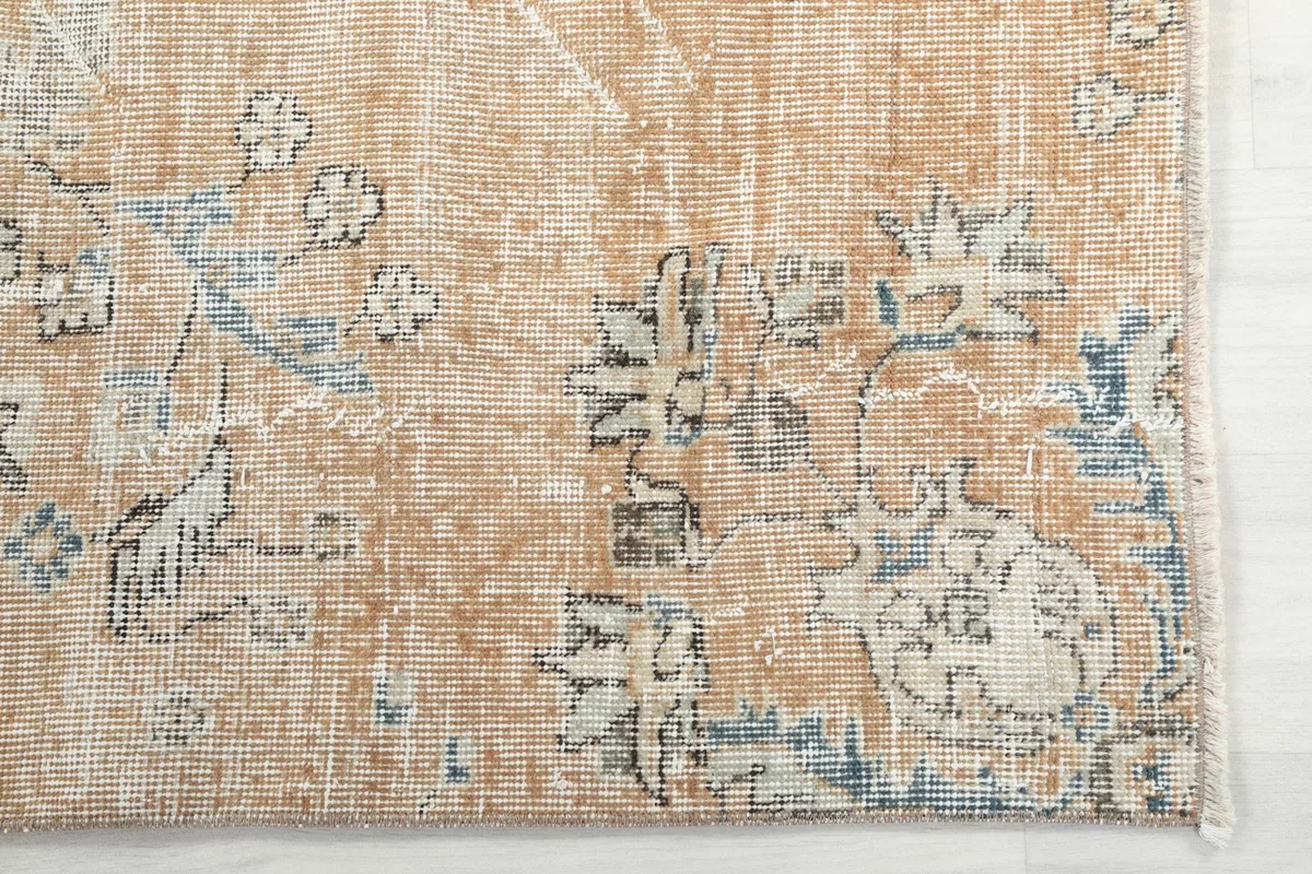Corner detail of the vintage rug, highlighting the distressed wool pile and intricate patterns