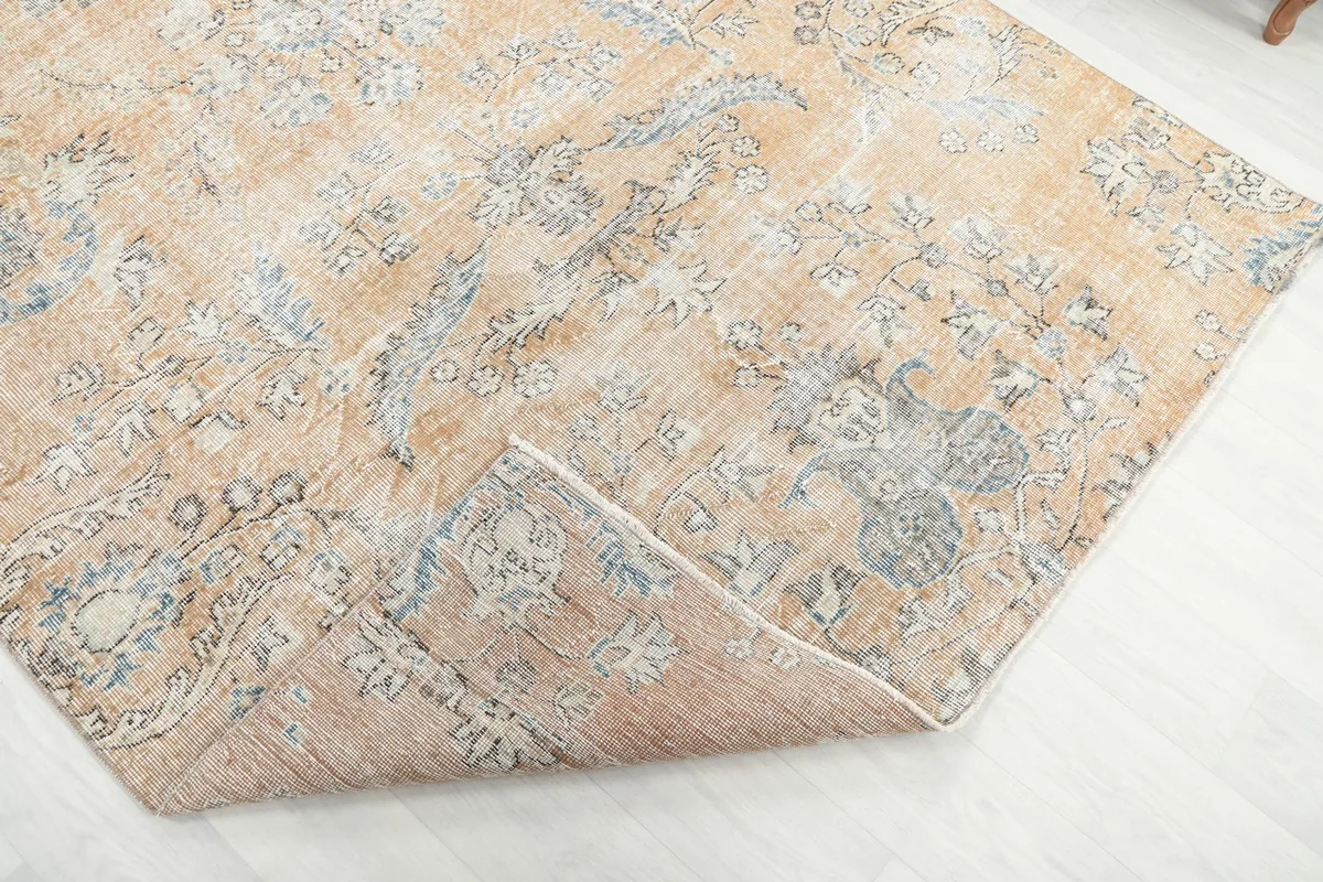 View of the rug with a corner folded back, showing the thickness of the hand-knotted wool pile