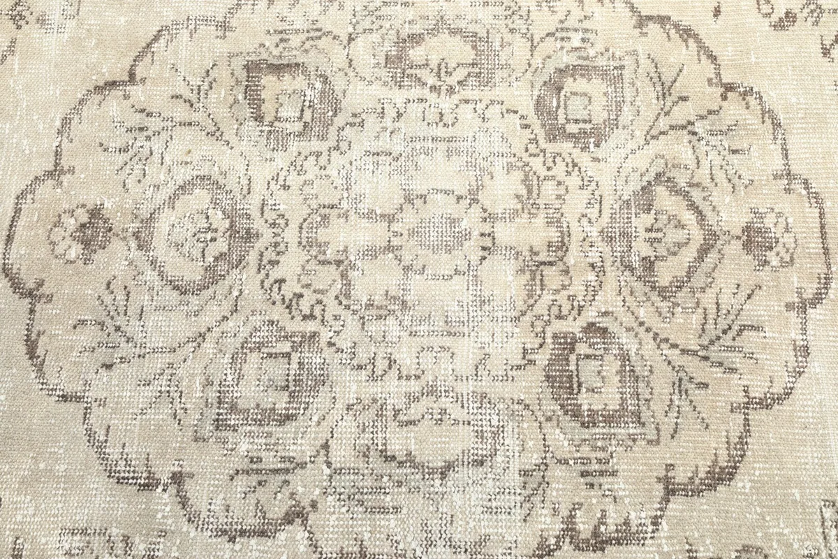 Close-up of the central gray medallion motif on the beige vintage rug