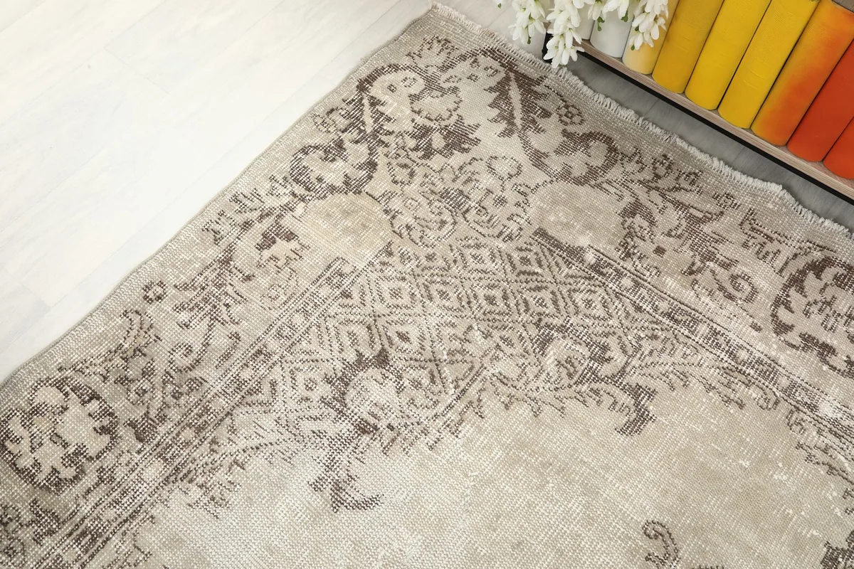 Detailed view of the intricate gray patterns and border elements on the beige vintage rug