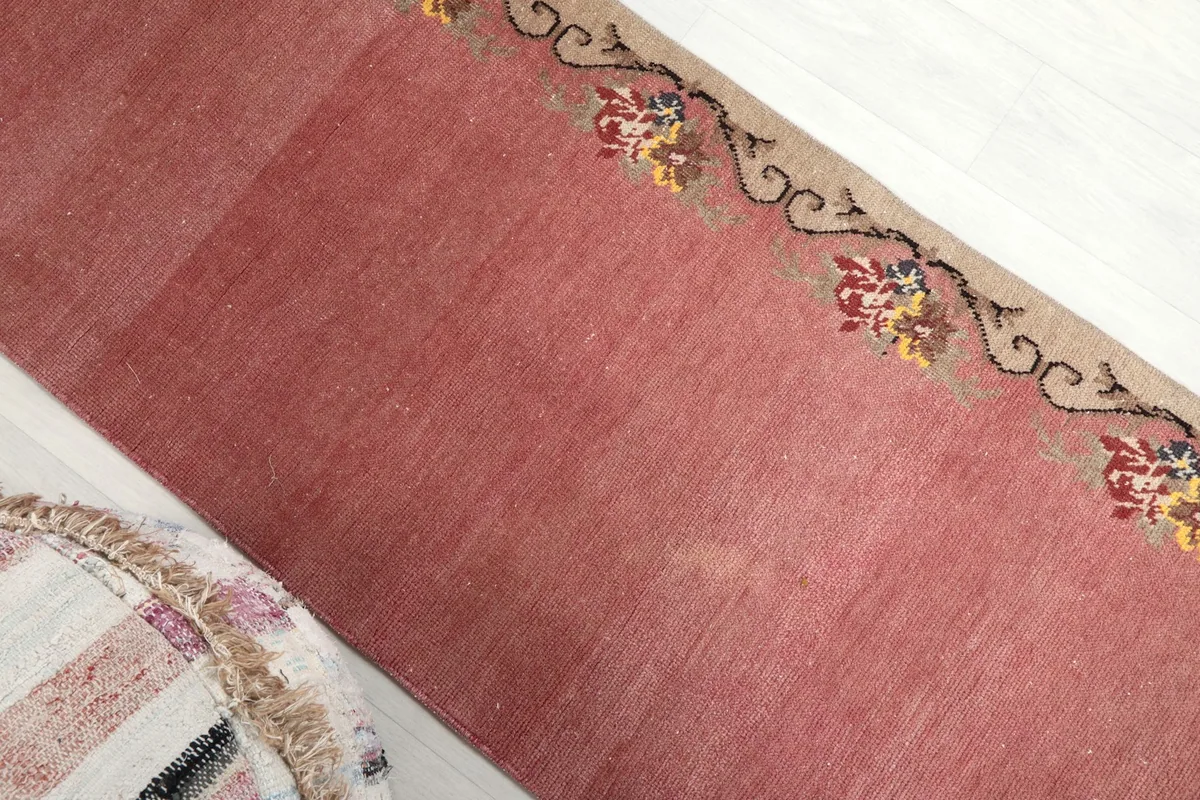 Angled view of the pink runner rug showing its length and floral border design