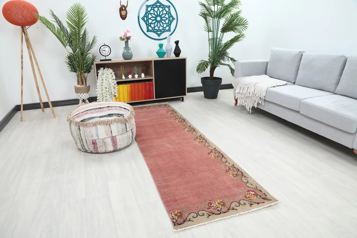 Angled view of the pink runner rug in a room with a sofa and plants
