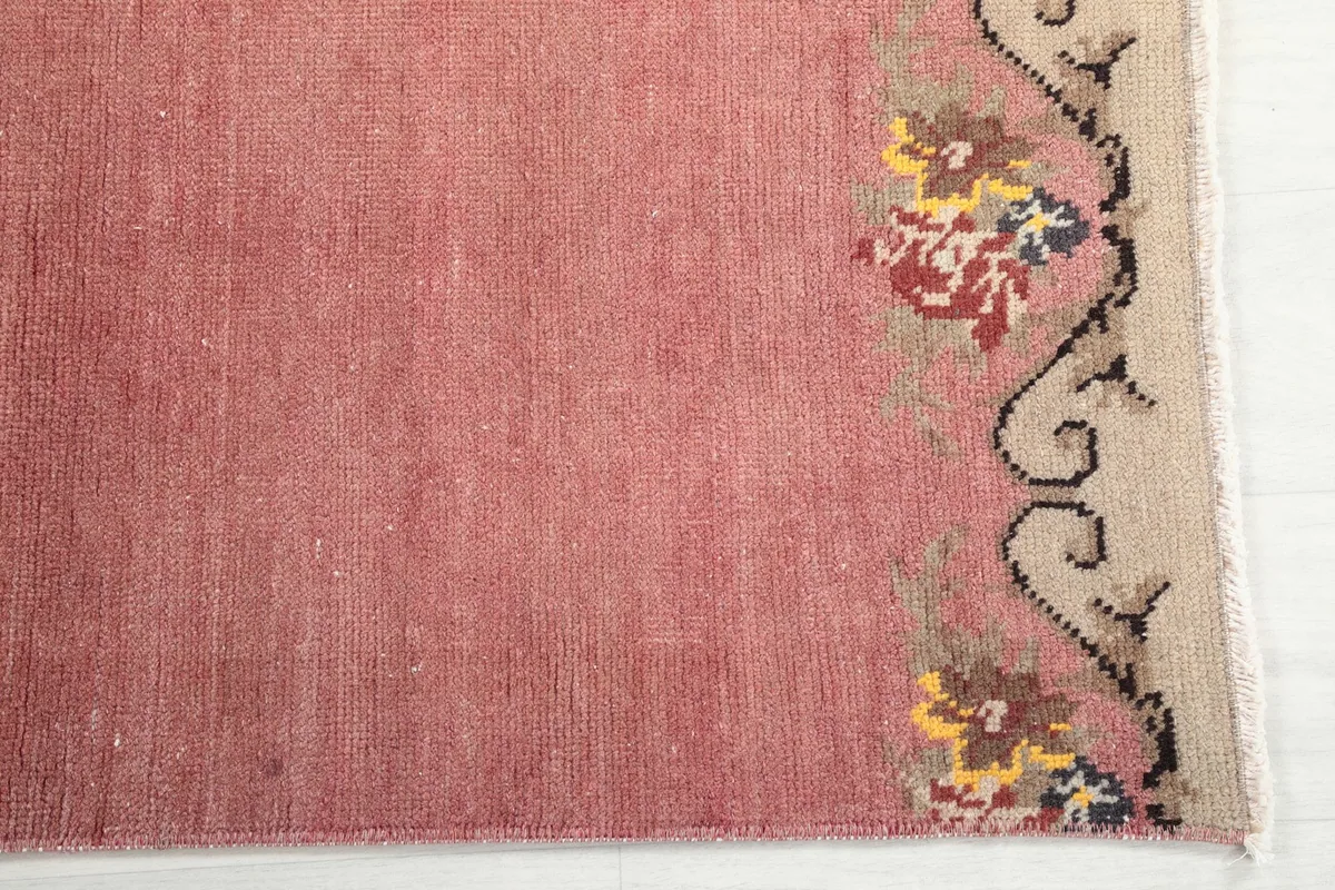 Detailed view of the pink rug's field and one section of the multicolor floral border