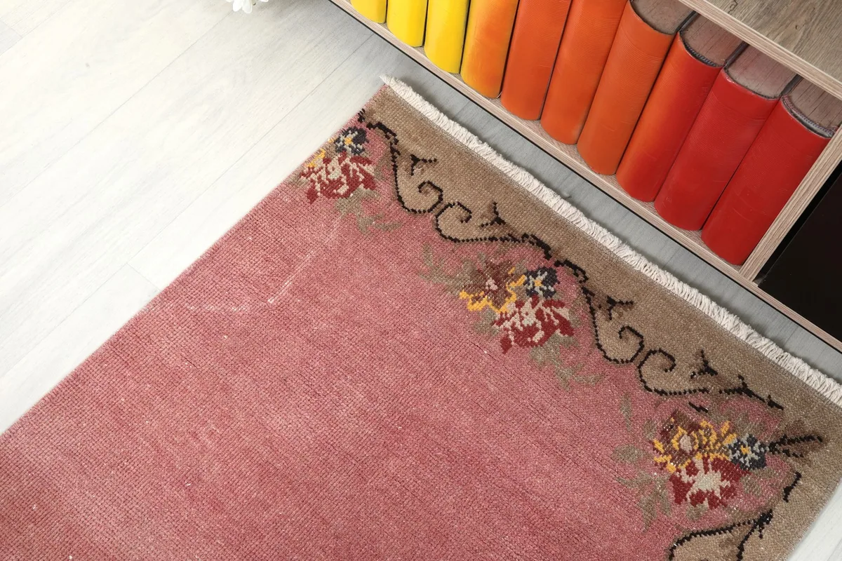 Overhead view of one end of the pink runner rug, showing the floral border pattern