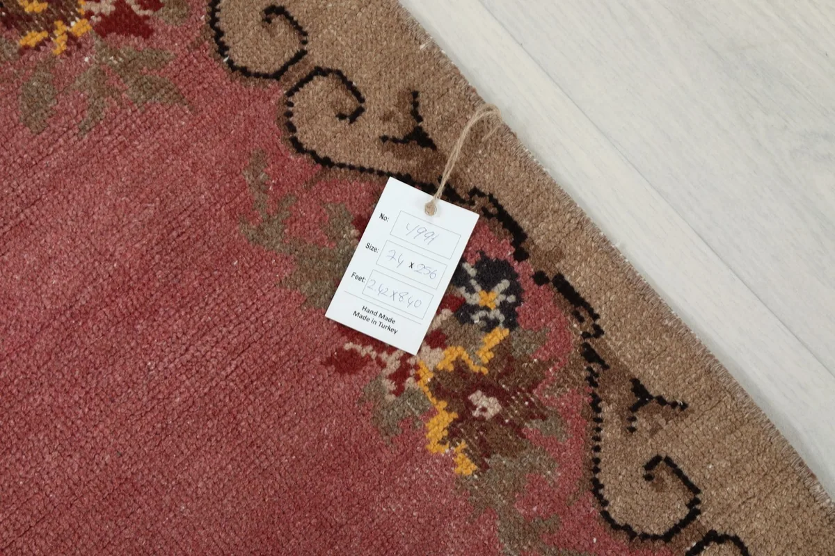 Close-up of the pink runner rug's border with a product tag attached
