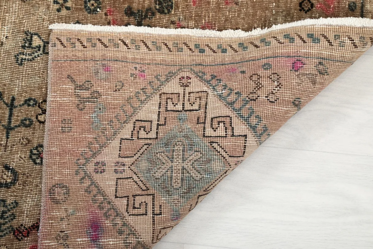 Close-up of a folded corner revealing the low wool pile and cotton foundation of the rug