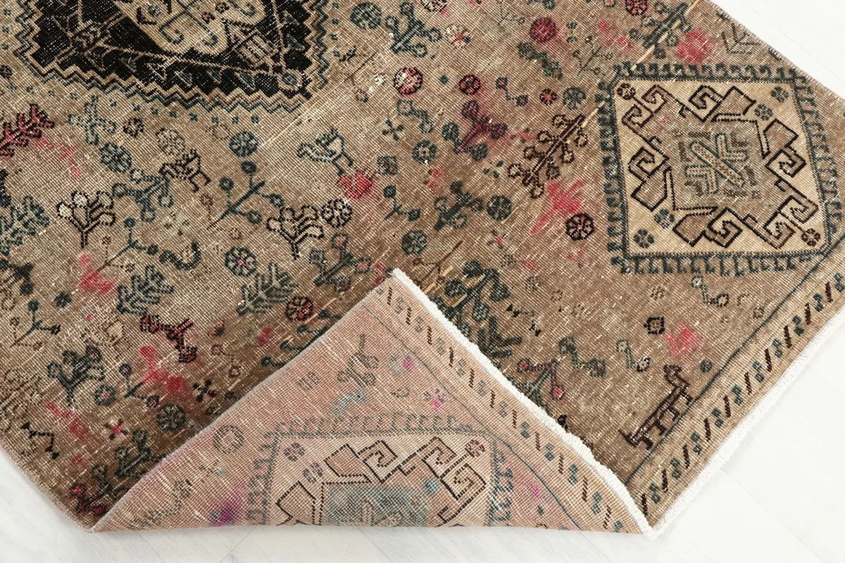 Folded corner showing the reverse side of the hand-knotted wool rug and foundation