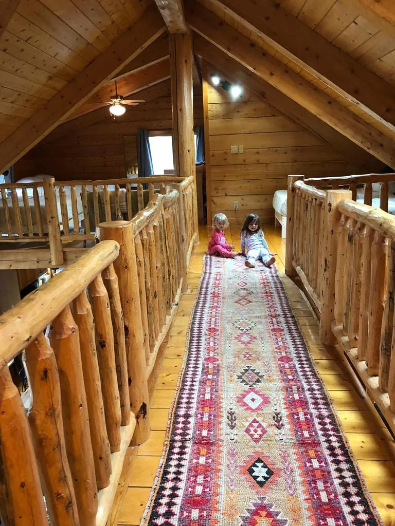 Children playing on a vintage Anatolian runner in a log-cabin loft